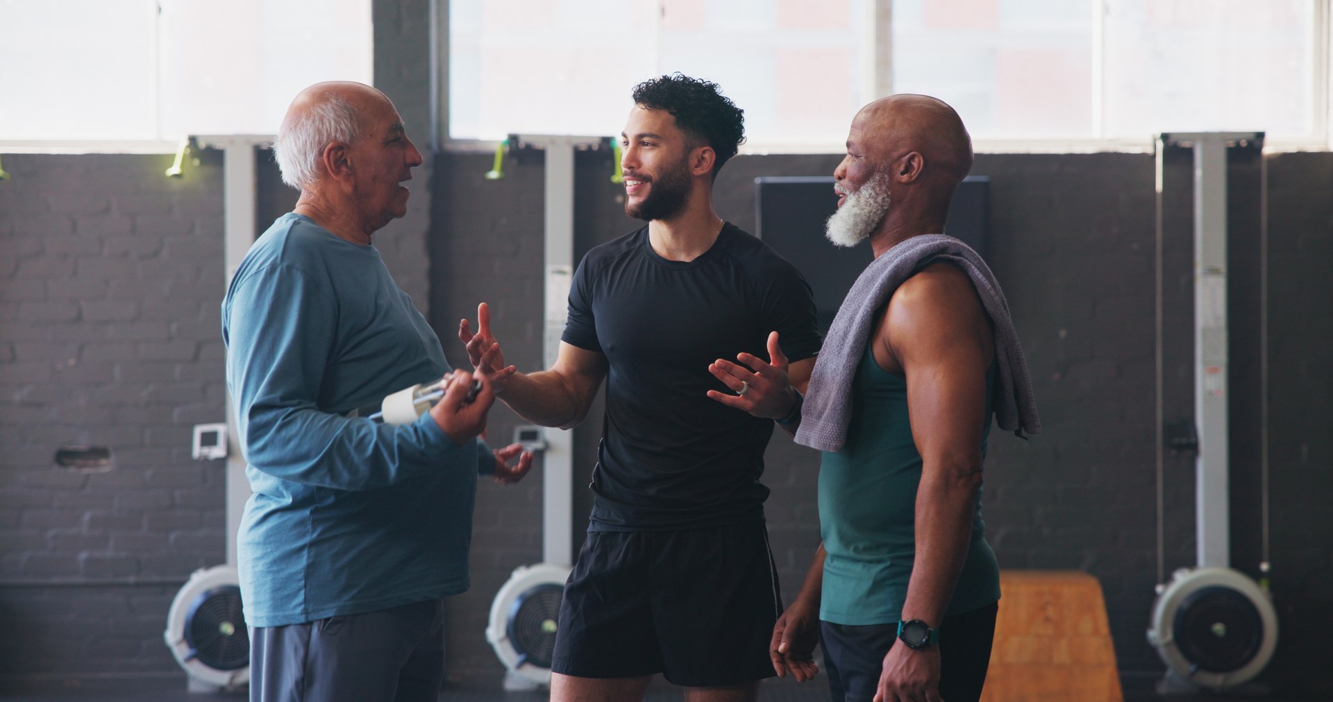 Three men talking together in a gym, representing peer support in recovery.
